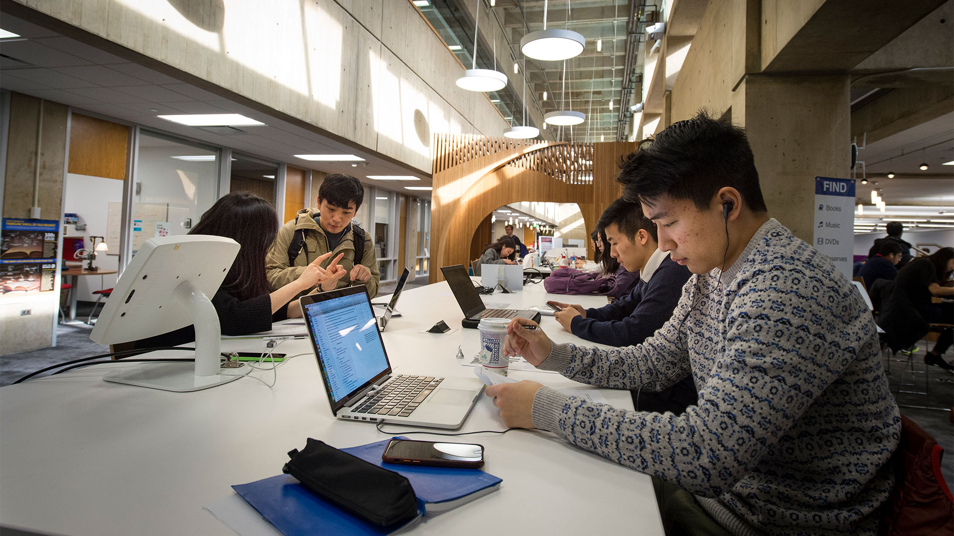 Student sitting at a library working on their laptop computers