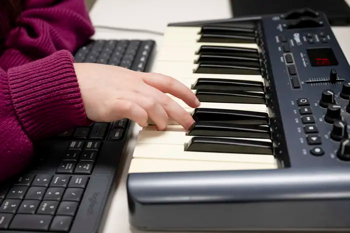 A person's hand on the piano keyboard, playing two notes