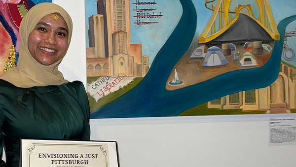 Samiha Islam stands in front of a painting she created.